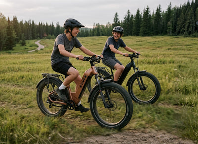 Boys riding through a grass field on CCM Nahanni Step through eBikes All-terrain